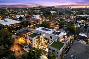 A modern building with a rooftop garden, multiple floors, and a parking area. - Free Gated Parking • Music Row Condo • Pool • Rooftop Club Room with Pool Table (Nashville)