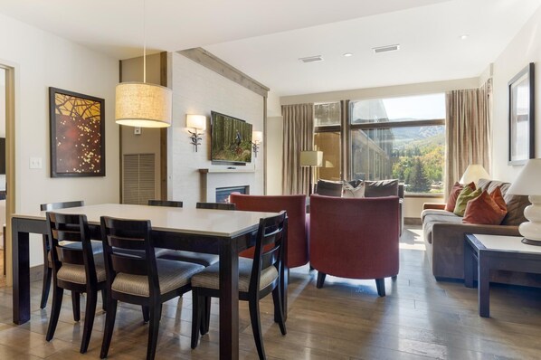 A modern hotel room with a dining area, a sofa, and a large window with a view. - Riverfront Resort & Spa 421a, 1BD Condo With Mtn Views (Avon)
