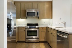 A kitchen with stainless steel appliances, wooden cabinets, and a marble countertop. - Riverfront Resort & Spa 421a, 1BD Condo With Mtn Views (Avon)
