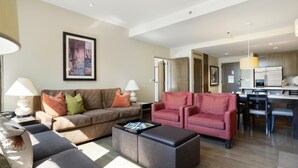 A modern living room with a sofa, armchairs, a coffee table, and a dining area with a kitchen in the background. - Riverfront Resort & Spa 421a, 1BD Condo With Mtn Views (Avon)