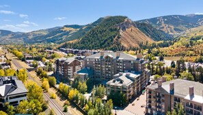 A mountainous town with modern buildings, a train track, and a prominent hill in the background. - Riverfront Resort & Spa 421a, 1BD Condo With Mtn Views (Avon)