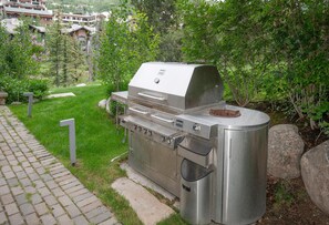 A stainless steel outdoor grill with a built-in smoker, located in a landscaped garden area with a paved walkway. - 725a Forest Road 4BD Home on Vail Mountain (Vail)