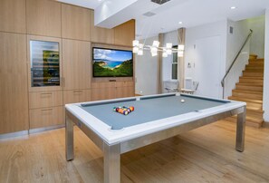 A pool table with a television above it, wooden cabinets, and a staircase. - 725a Forest Road 4BD Home on Vail Mountain (Vail)