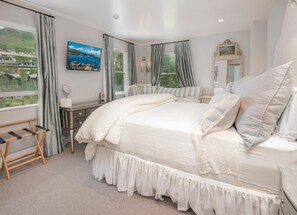 A bedroom with a large bed, a desk, a mirror, and a view of the outdoors. - 725a Forest Road 4BD Home on Vail Mountain (Vail)