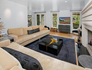 A modern living room with a sofa, coffee table, and fireplace. - 725a Forest Road 4BD Home on Vail Mountain (Vail)
