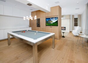 A modern room with a pool table, a mounted TV, and a seating area with chairs. - 725a Forest Road 4BD Home on Vail Mountain (Vail)