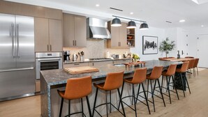 Uma cozinha moderna com eletrodomésticos de aço inoxidável, uma ilha de mármore e banquetas.