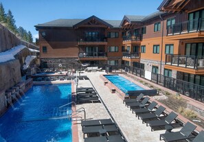 Ein Hotel mit Poolbereich, mehreren Balkonen und einer steinernen Fassade.