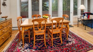 A dining area with a wooden table and chairs, a chandelier, and a patterned rug. - Sun Vail 23a, 2BD Condo With Vail Mountain Views (Vail)