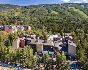 A resort with multiple buildings, a parking area, and a mountainous backdrop. - Vail International 111, 2 BD Lionshead Village Condo (Vail)