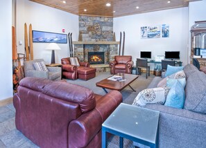 A living room with leather sofas, a stone fireplace, and a television. - Vail International 111, 2 BD Lionshead Village Condo (Vail)
