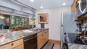 Una cocina moderna con lavavajillas, electrodomésticos de acero inoxidable y un amplio ventanal con vista a una terraza.