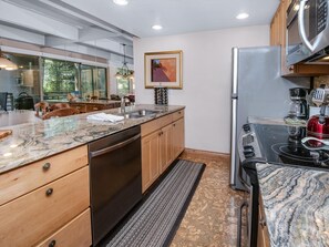 A modern kitchen with a dishwasher, stainless steel appliances, and a large window overlooking a deck. - Vail International 111, 2 BD Lionshead Village Condo (Vail)