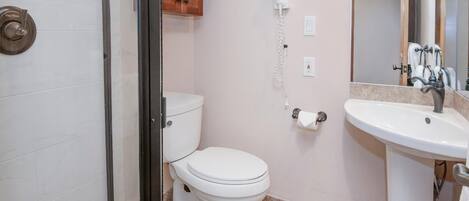 Et badeværelse med toilet, bruser og vask.