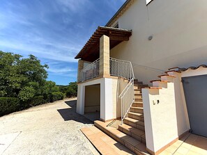 Ein zweistöckiges Haus mit Balkon, Treppe und Garage.