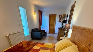 A bedroom with a large bed, a sofa, a desk, and a window. - "Le Colombier" 3★ Air-Conditioned Vacation Rental - Peace and Nature in the Heart of the Vineyards (Vinsobres)