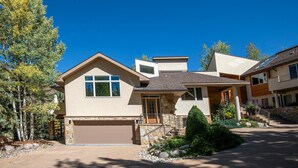Ein modernes, zweistöckiges Haus mit Garage, Steinaußenwand und begrüntem Auffahrt.