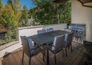 Eine Terrasse im Freien mit Grill, Tisch und Stühlen.