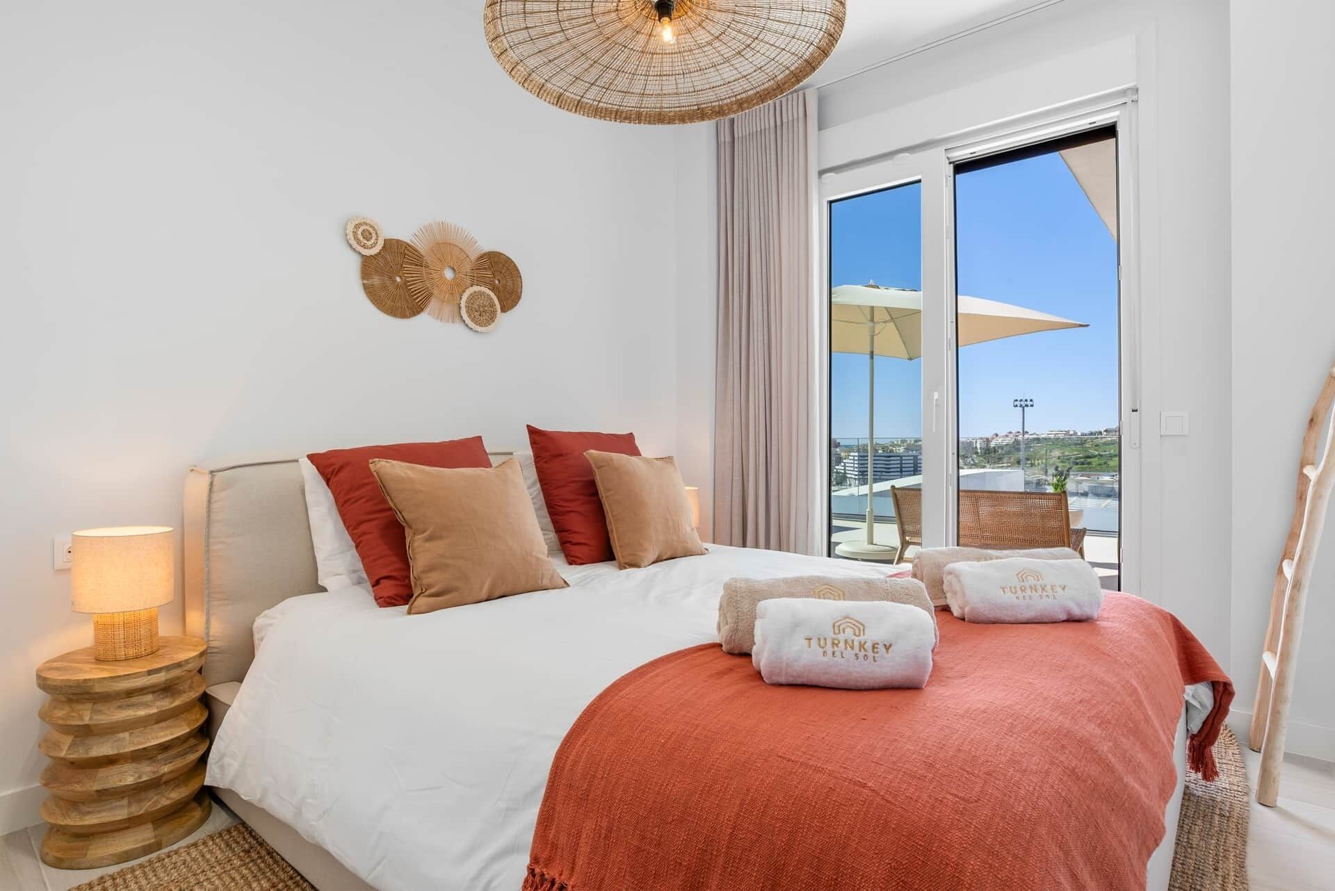 A hotel room with a bed, a nightstand, a lamp, a large window with a view, and a ceiling light.