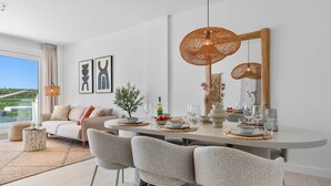 Ein moderner Essbereich mit einem runden Tisch, Stühlen und einer großen, gewebten Leuchte.