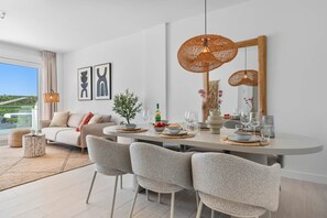 Ein moderner Essbereich mit einem runden Tisch, Stühlen und einer großen, gewebten Leuchte.