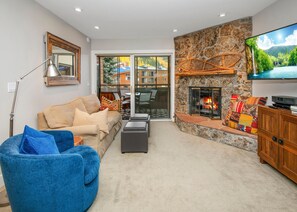 Ein Wohnzimmer mit Sofa, blauem Sessel, Kamin, Fernseher und einer Steinwand.