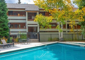 Ein Wohngebäude mit Pool, Außenbereich und einem Baum mit gelben Blättern.