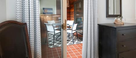 A room with a sliding glass door leading to a patio, a dark wooden dresser, and a chair.