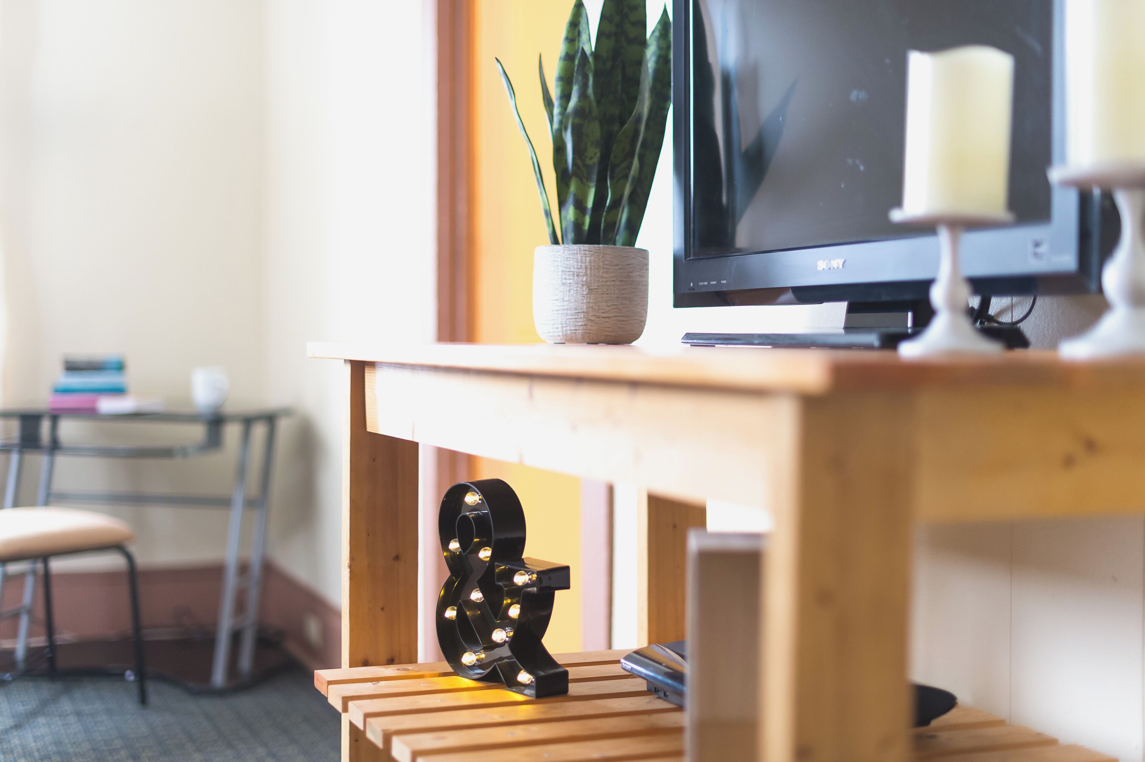 Un bureau en bois avec une télévision, une plante en pot et un objet décoratif.