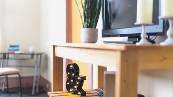 Un bureau en bois avec une télévision, une plante en pot et un objet décoratif.