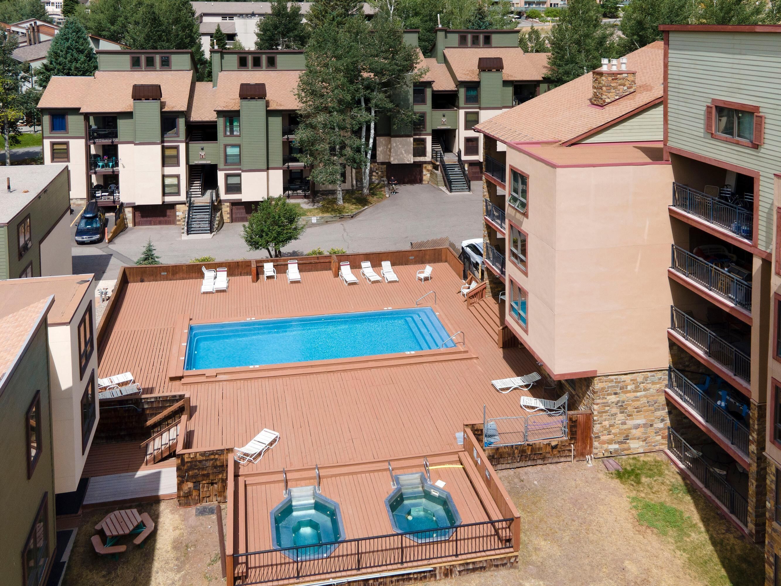 Area piscina sul tetto con poltronne prendisole, vasca idromassaggio e una scala che conduce ai piani superiori.