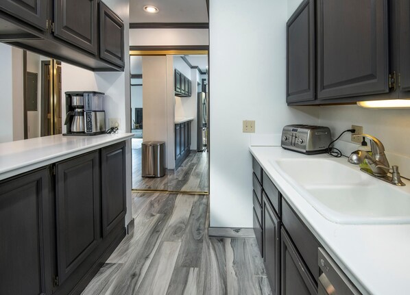A modern kitchen with dark cabinets, a white countertop, a stainless steel trash can, a toaster, and a sink with a faucet. - Breakaway West 222, 2BD Vail Condo (Vail)