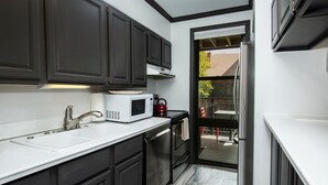 A modern kitchen with dark cabinets, a white countertop, a microwave, a sink, and a view of the outdoors. - Breakaway West 222, 2BD Vail Condo (Vail)