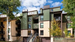 A multi-story residential building with a central staircase, balconies, and a small garden area. - Breakaway West 222, 2BD Vail Condo (Vail)