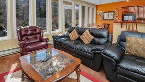 A living room with a leather sofa, a glass coffee table, and a red armchair. - Sun Vail 12e, 2BD Condo With Vail Mountain Views (Vail)