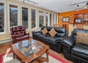 Ein Wohnzimmer mit einem Ledersofa, einem Glastisch und einem roten Sessel.
