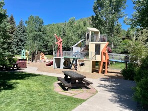 Ein Spielplatz mit Rutschen, Klettergerüsten und Picknicktischen.