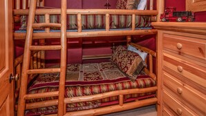 Ein Stockbett mit einer Leiter, eine Holzkommode und ein Spielzug oben drauf.