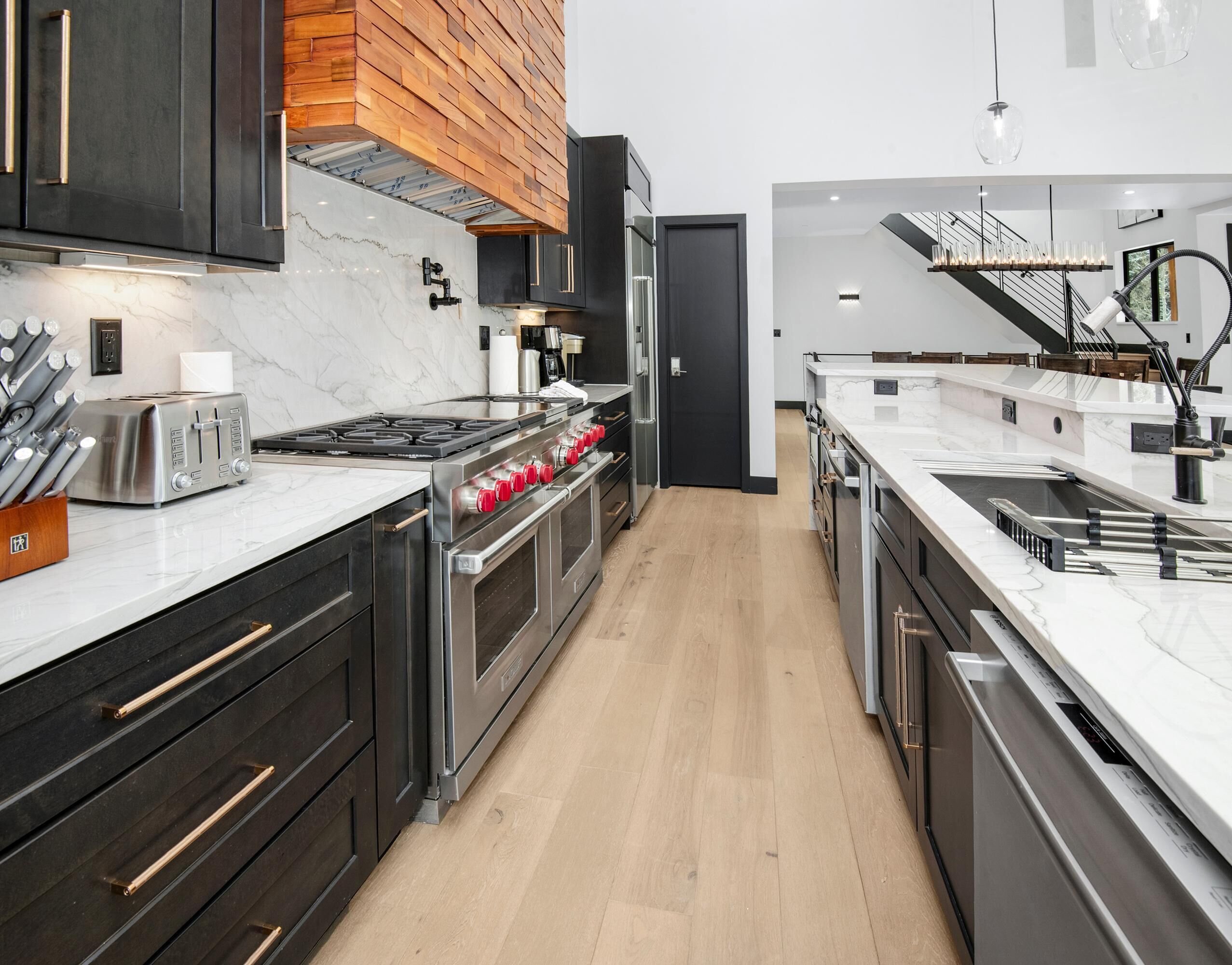 A modern kitchen with a central island, stainless steel appliances, and a wooden accent wall.