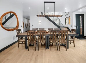 A dining area with a large wooden table, chairs, a mirror, and a staircase. - Big Horn House, 4387 Columbine (Vail)