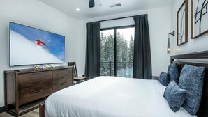 Ein Schlafzimmer mit einem großen Bett, einem Schminktisch, einem Flachbildfernseher und Blick auf einen Balkon.