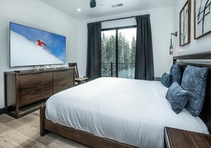 Ein Schlafzimmer mit einem großen Bett, einem Schminktisch, einem Flachbildfernseher und Blick auf einen Balkon.