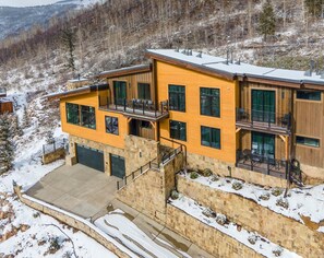 A modern two-story building with a stone base, large windows, and balconies. - Big Horn House, 4387 Columbine (Vail)