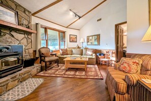 A cozy living room with a stone fireplace, a sofa, a patterned rug, and a wooden coffee table. - Sky Valley Views! Deck, Golf, 2 Kings (Dillard)