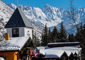 A snow-covered mountain village with a church, flags, and traditional buildings. - Spruce Way 209, 2BD East Vail Condo (Vail)
