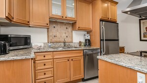A kitchen with wooden cabinets, a stainless steel refrigerator, a dishwasher, a microwave, and granite countertops. - Spruce Way 209, 2BD East Vail Condo (Vail)