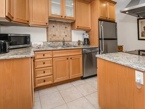 A kitchen with wooden cabinets, a stainless steel refrigerator, a dishwasher, a microwave, and granite countertops. - Spruce Way 209, 2BD East Vail Condo (Vail)