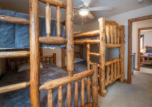 A bunk bed room with a ceiling fan, wooden railings, and a carpeted floor. - Spruce Way 209, 2BD East Vail Condo (Vail)