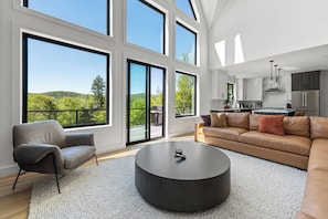 Ein modernes Wohnzimmer mit einem großen Fenster, einem runden Couchtisch und einem Sofa.