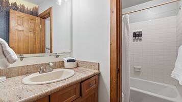 Un baño con lavamanos, espejo y ducha.